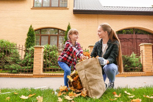 Anne ve kızı sonbahar yapraklarını dışarıda temizliyorlar. — Stok fotoğraf