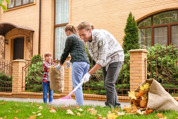 Family cleaning up autumn leaves outdoors — Stock Photo, Image