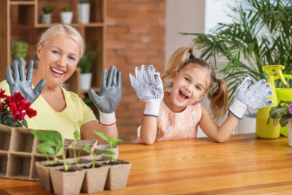 Menina e avó felizes vestindo luvas de jardinagem em casa — Fotografia de Stock