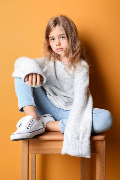 Söt fashionabel flicka sitter nära färg vägg — Stockfoto