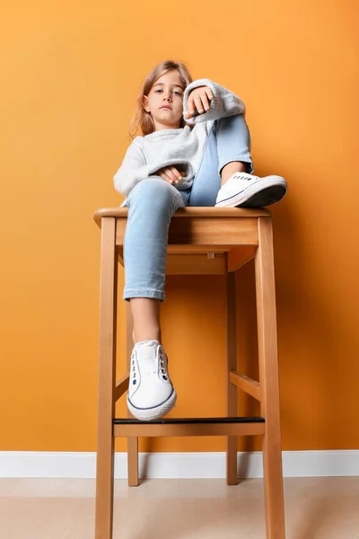 Cute fashionable girl sitting near color wall — Stock Photo, Image