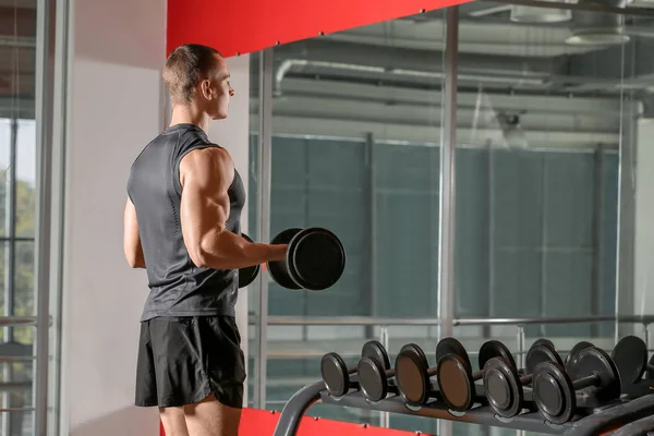 Deportivo musculoso hombre de entrenamiento con mancuernas en el gimnasio — Foto de Stock