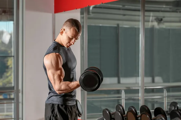 Deportivo musculoso hombre de entrenamiento con mancuernas en el gimnasio — Foto de Stock