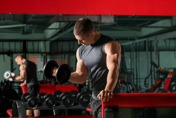 Sporty muscular man training with dumbbells in gym — Stock Photo, Image