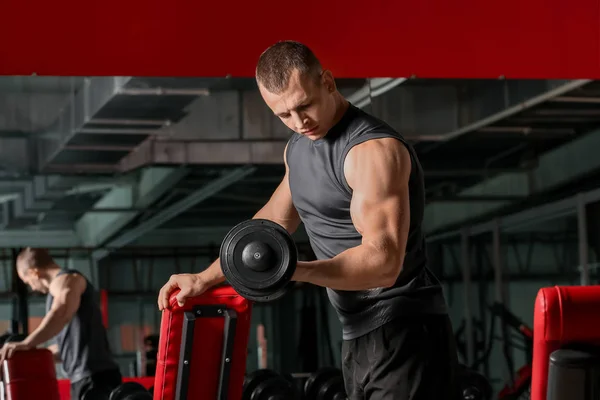 Sporty muscular man training with dumbbells in gym — Stock Photo, Image