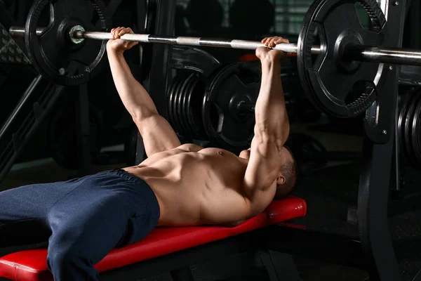 Deportivo musculoso hombre de entrenamiento con barra de pesas en gimnasio —  Fotos de Stock