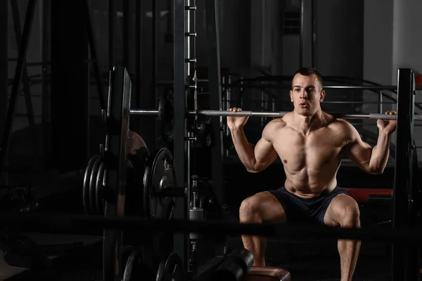 Deportivo musculoso hombre de entrenamiento con barra de pesas en gimnasio — Foto de Stock