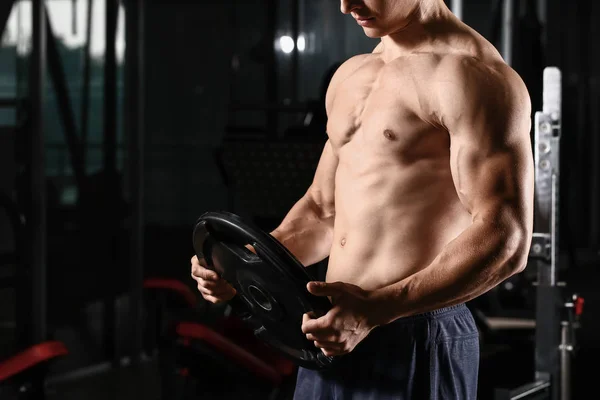 Sporty muscular man training with barbell plate in gym — Stock Photo, Image