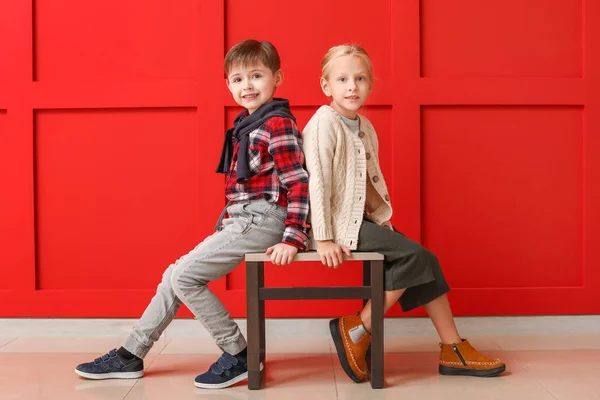 Cute little children in autumn clothes sitting near color wall — Stock Photo, Image