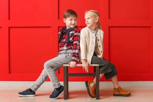 Cute little children in autumn clothes sitting near color wall — Stock Photo, Image