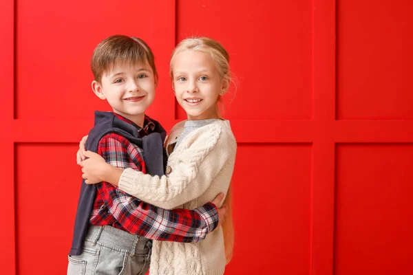 Cute little children in autumn clothes hugging near color wall — Stock Photo, Image