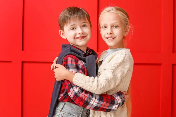 Cute little children in autumn clothes hugging near color wall — Stock Photo, Image
