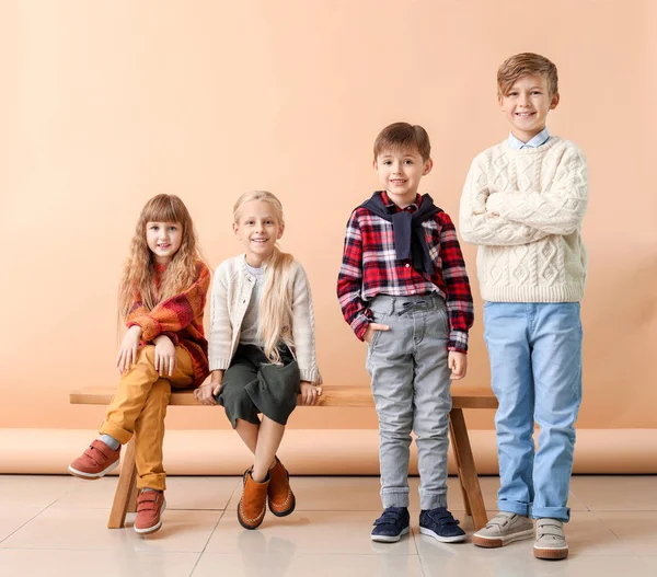 Bambini piccoli e carini in abiti autunnali vicino alla parete di colore — Foto Stock