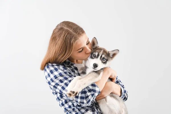 Cute teenage girl with funny husky puppy on light background — Stock Photo, Image