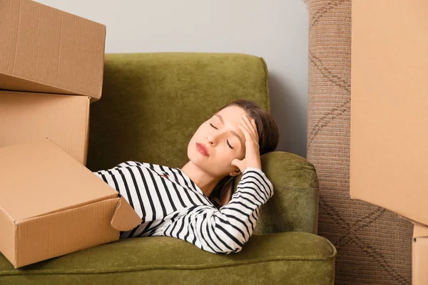 Yeni evdeki kanepeye yığınla kutu taşıyan yorgun kadın.