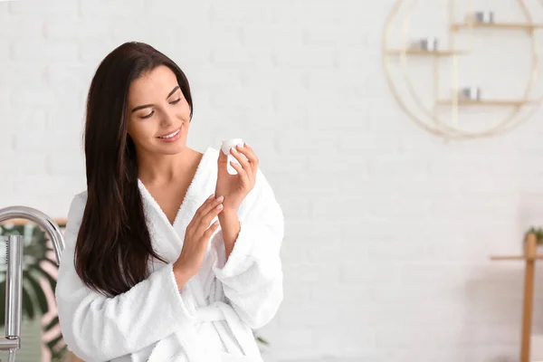 Beautiful young woman applying cream in bathroom — Stock Photo, Image