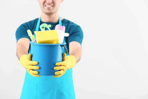 Janitor com suprimentos de limpeza em fundo claro — Fotografia de Stock