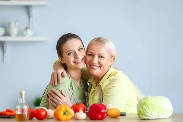 Mature woman and her adult daughter together in kitchen — Stock Photo, Image