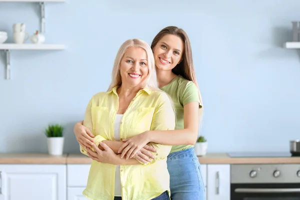 Mature woman and her adult daughter together in kitchen — Stock Photo, Image