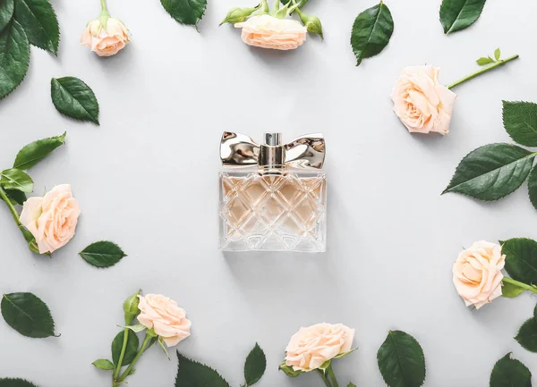 Garrafa de perfume com flores de rosa no fundo branco — Fotografia de Stock