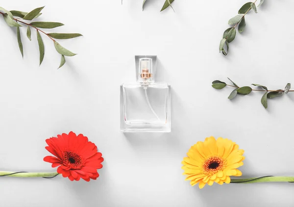 Butelka perfum z kwiatami i liśćmi na białym tle — Zdjęcie stockowe