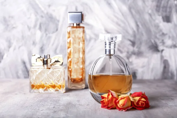 Botellas de perfumes con flores de rosas sobre fondo grunge —  Fotos de Stock