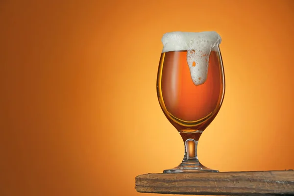 Glass of fresh beer on table against color background — Stock Photo, Image