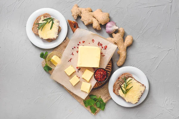 Tasty butter with spices and bread on grey background — Stock Photo, Image