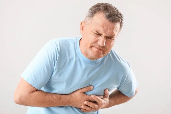 Mature man suffering from heart attack on white background — Stock Photo, Image