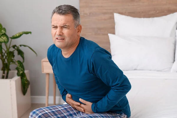 Starší muž trpící bolestí břicha v ložnici — Stock fotografie