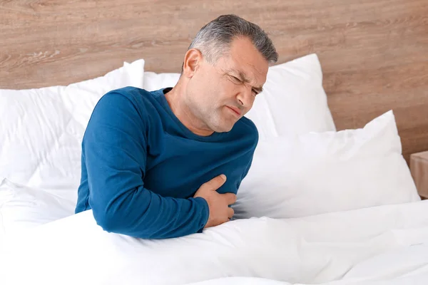 Mature man suffering from heart attack in bedroom — Stock Photo, Image