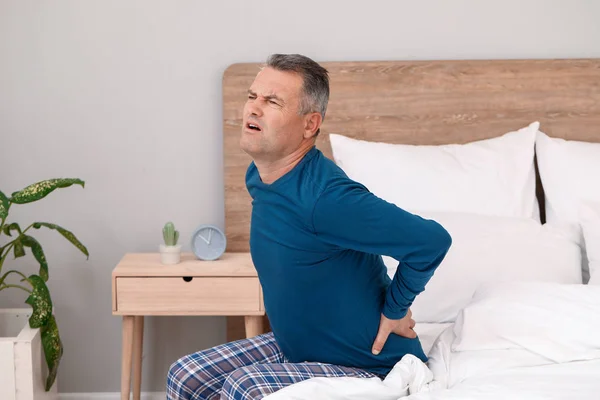 Mature man suffering from back pain in bedroom — Stock Photo, Image