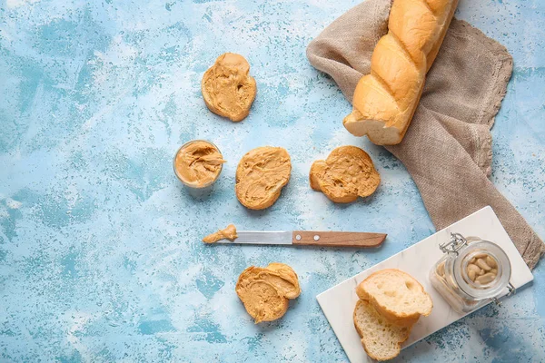 Pan fresco y sabrosa mantequilla de maní sobre fondo de color —  Fotos de Stock