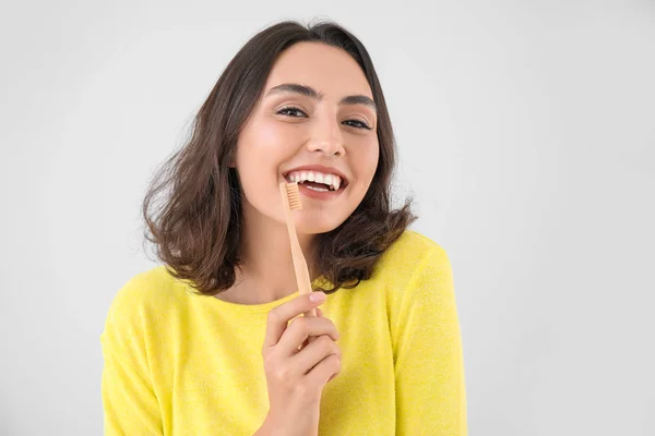 Bella giovane donna con spazzolino da denti su sfondo chiaro — Foto Stock