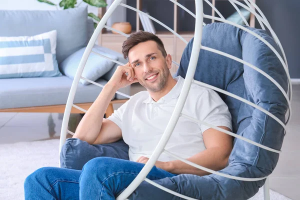 Hombre guapo sentado en sillón en casa — Foto de Stock