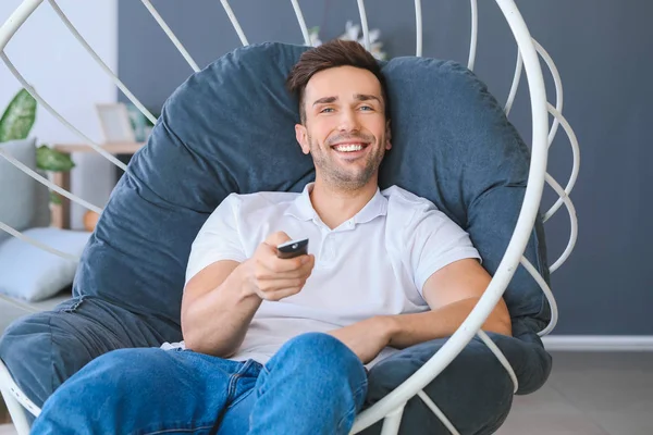 Handsome man watching TV while sitting in armchair at home — Stock Photo, Image