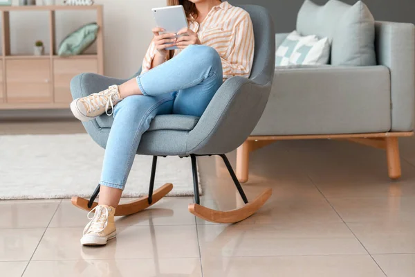 Beautiful woman with tablet computer sitting in armchair at home — Stock Photo, Image