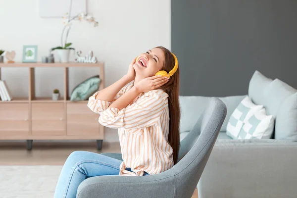 Krásná žena poslouchá hudbu, zatímco sedí v křesle doma — Stock fotografie