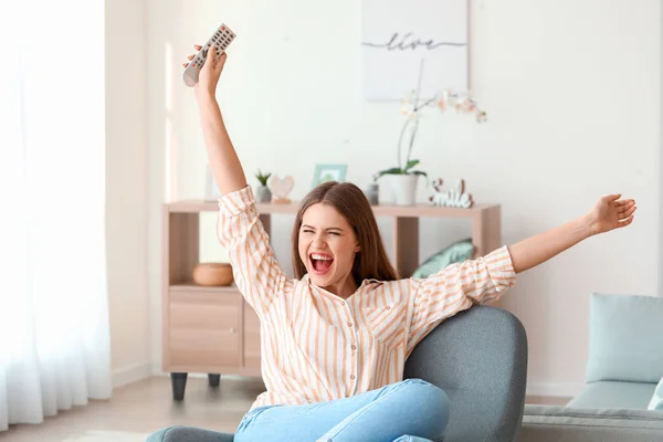 Mulher feliz assistindo TV enquanto sentado em poltrona em casa — Fotografia de Stock