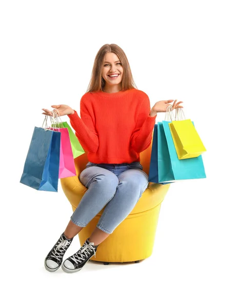 Beautiful woman with shopping bags sitting in armchair on white background — Stock Photo, Image