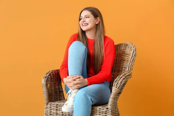Piękna kobieta siedzi w fotelu na kolorowym tle — Zdjęcie stockowe