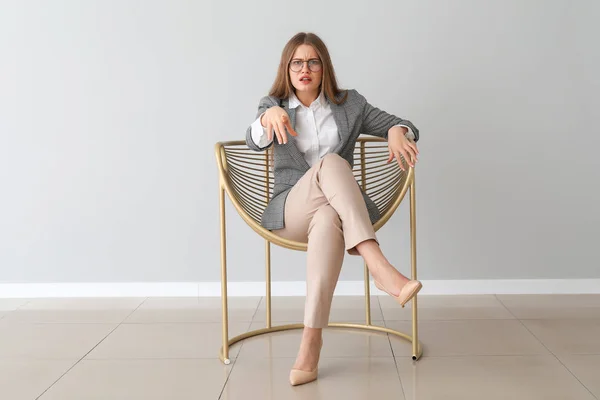 Bothered businesswoman sitting in armchair near light wall — 스톡 사진