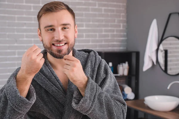 Hombre guapo que usa hilo dental en el baño — Foto de Stock
