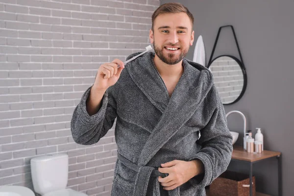 Handsome man brushing teeth in bathroom — Stock Photo, Image