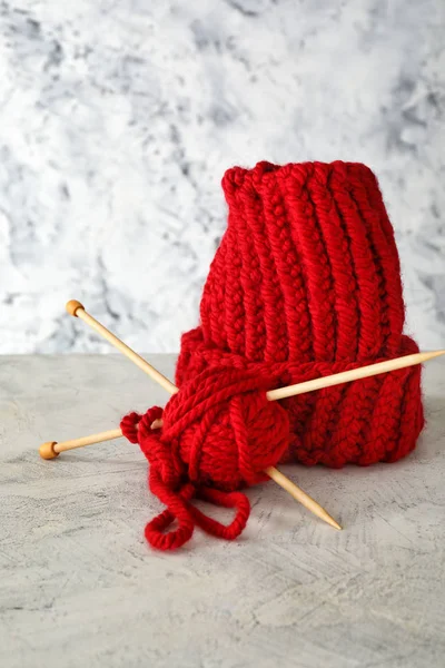 Half-finished hat with knitting yarn and needles on light background