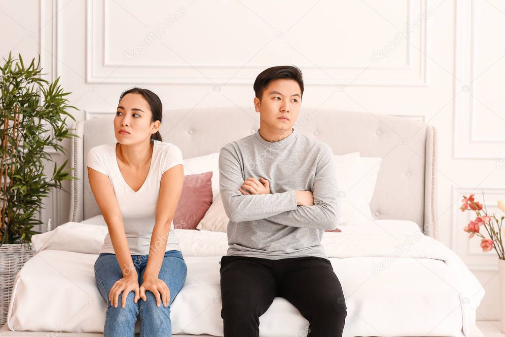 Quarreled Asian couple in bedroom
