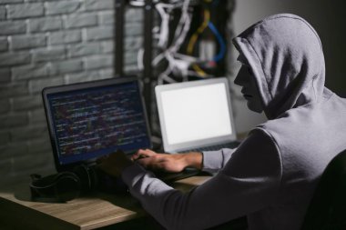 Karanlık odada dizüstü bilgisayar kullanan profesyonel bir hacker.