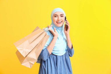 Alışveriş çantalı güzel bir Arap kadın. Arka planda cep telefonuyla konuşuyor.