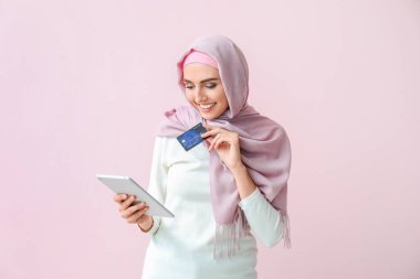 Tablet bilgisayarı ve renkli kredi kartı olan güzel bir Arap kadın.