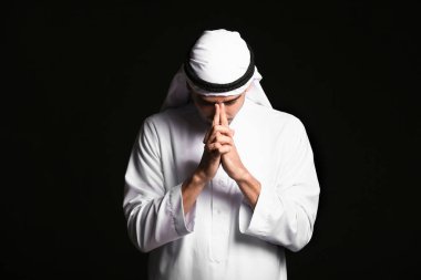 Siyah arka planda yakışıklı dua eden bir Arap.